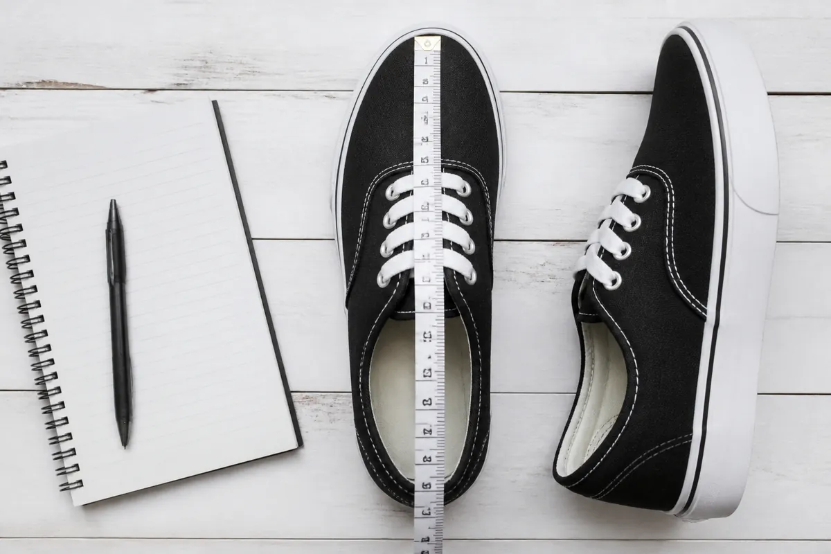 Vans shoe size chart flat lay with skate sneakers and heel-to-toe measuring tape